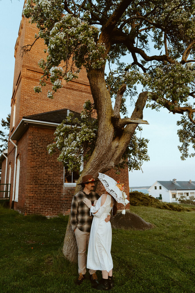 couple in wedding attire in fronbt of old school brick castle in port townsend 